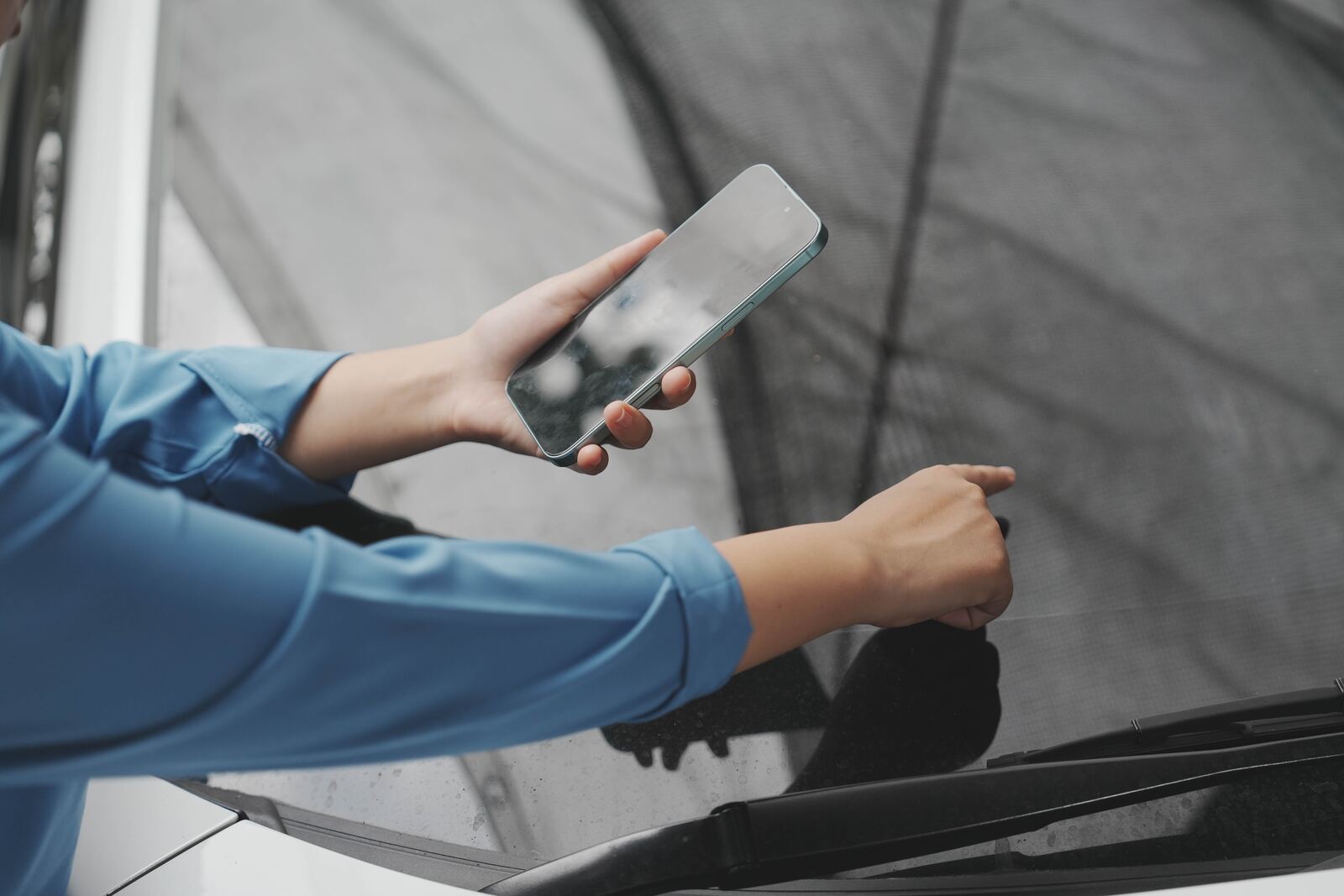 Person requesting a mobile auto glass quote on their phone next to a cracked windshield